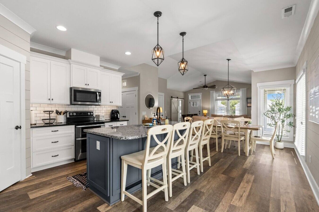 A kitchen with white cabinets, a central island with bar stools, and pendant lighting.