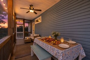A covered outdoor dining area with a table set for a meal, a ceiling fan, and a view of the outdoors. - The Crabby Buffalo𓇼Golf Cart+Outdoor Oasis+Cozy (Oak Island)