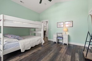 A bunk bed with a desk and chair, a ladder, and a door leading to another room. - The Crabby Buffalo𓇼Golf Cart+Outdoor Oasis+Cozy (Oak Island)
