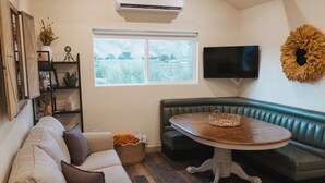 A cozy living room with a sofa, a round table, and a television.