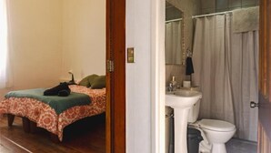 Un dormitori amb un llit, una taula de nit i un gat.