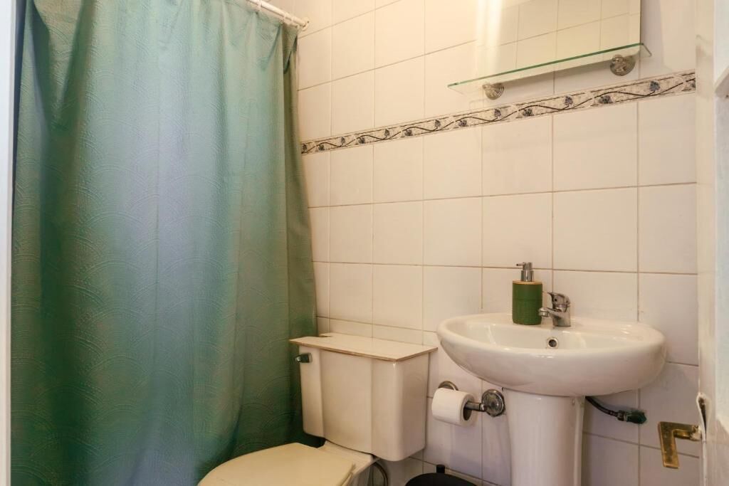 Un baño con inodoro, lavabo y cortina de ducha.