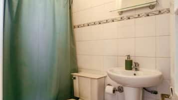 Un baño con inodoro, lavabo y cortina de ducha.