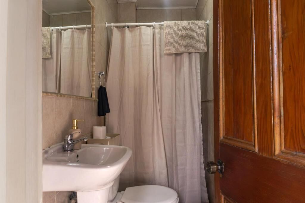 A bathroom with a white sink, a toilet, and a shower curtain.