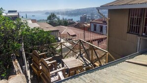 Vista de un paisaje urbano costero con edificios, una terraza de madera y una escalera metálica.