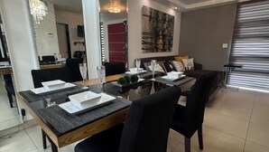 Un espace repas agrémenté d’un lustre, d’une table à manger dressée pour quatre personnes et d’un décor intérieur moderne.
