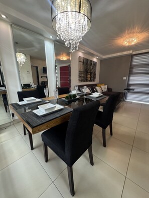 A dining area with a chandelier, a dining table set for four, and a modern interior design.