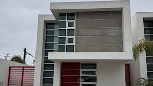 Un bâtiment moderne à deux étages, doté d’une porte rouge, de grandes fenêtres et d’une allée en béton.