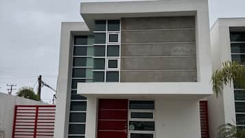 Un bâtiment moderne à deux étages, doté d’une porte rouge, de grandes fenêtres et d’une allée en béton.