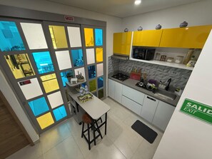 Eine moderne Küche mit einer zentralen Kochinsel, gelben Schränken und einer gefliesten Spritzschutzwand.