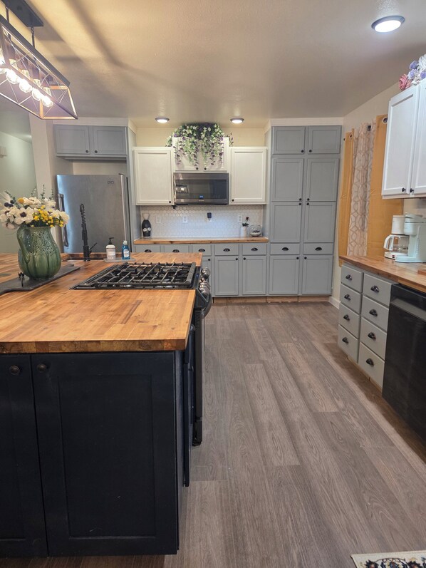 A modern kitchen with a central island, stainless steel appliances, and light wood flooring.