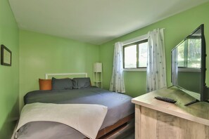 Une chambre avec un lit, une télévision et une fenêtre avec des rideaux.