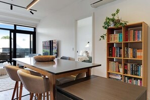 Ein modernes Interieur mit Essbereich, Bücherregal und Blick durch eine Glastür.