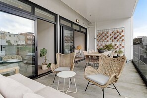 Een balkon met rieten meubilair, een eettafel en potplanten.