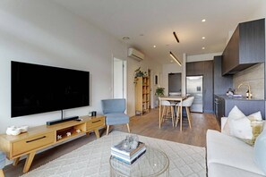 Ein modernes Wohnzimmer mit Fernseher, Couchtisch und Sofa.