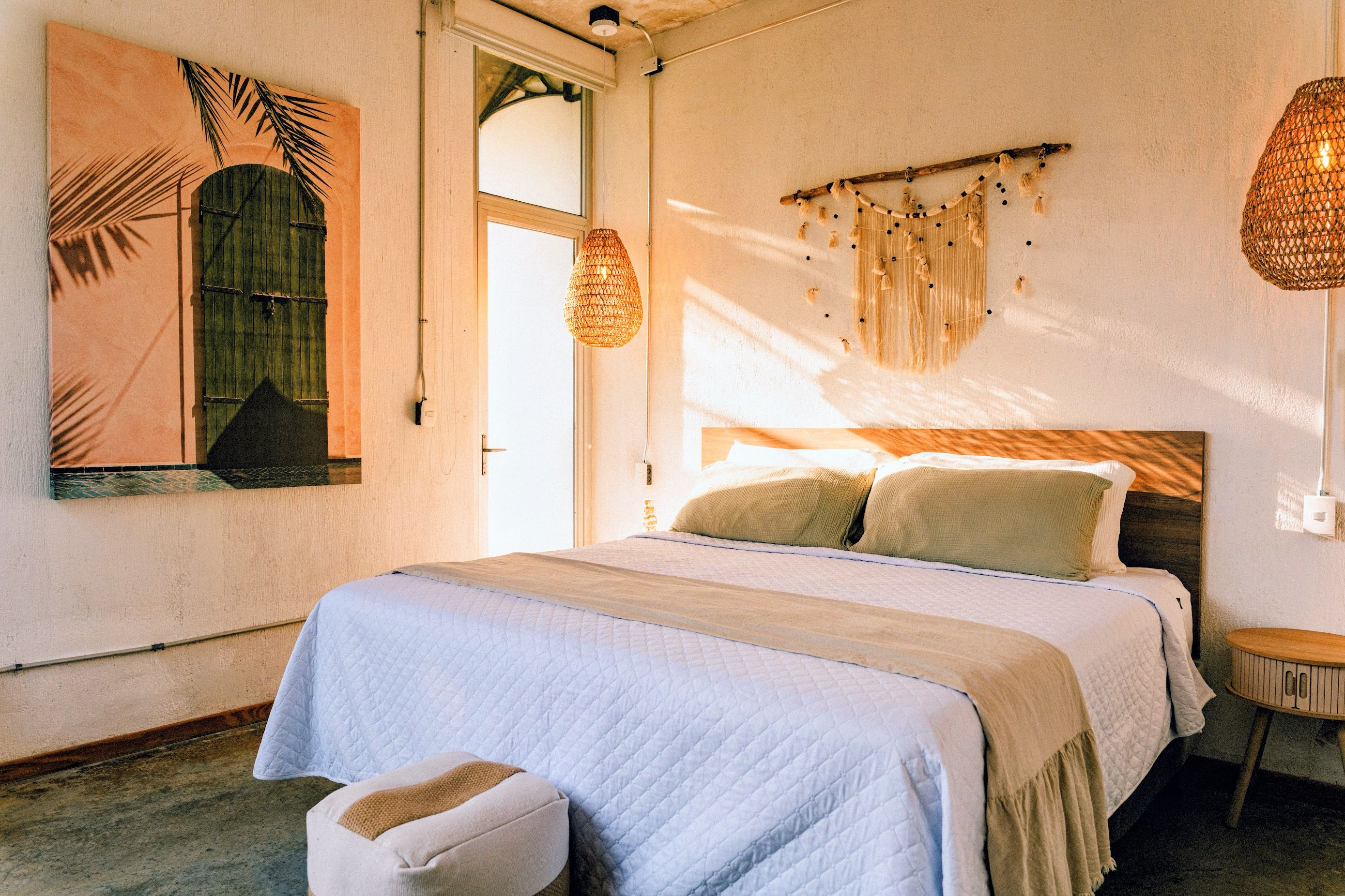 A bedroom with a bed, a bedside table, a hanging light fixture, and a wall-mounted decorative piece.