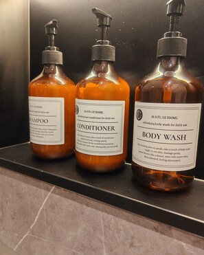 Three bottles of personal care products on a shelf. - Boutique Luxury Luton | King Bed | Sleeps 4 | Near Airport & Station (Luton)