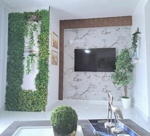 A modern living room with a large TV, a wall-mounted plant, and a decorative silver sculpture. - You San Juan Escape Awaits- Spacious 3 Bedroom Retreat (San Juan)