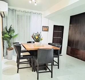 A modern dining area with a wooden table, black chairs, and a potted plant. - You San Juan Escape Awaits- Spacious 3 Bedroom Retreat (San Juan)