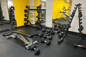 Et fitnesscenter med vægte, træningsbænke og håndvægte.