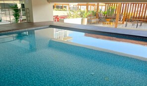 A clear indoor swimming pool with tiled flooring, surrounded by lounge seating and potted plants. - Cozy 1-bedroom 80m2 apartment in Miraflores with pool (Miraflores)