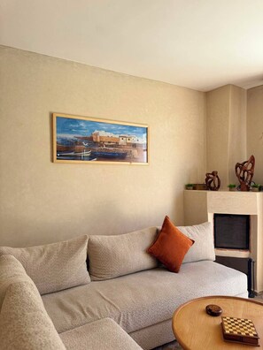 Ein Wohnzimmer mit einem beigen Sofa, einem gerahmten Bild an der Wand und einem Kamin.