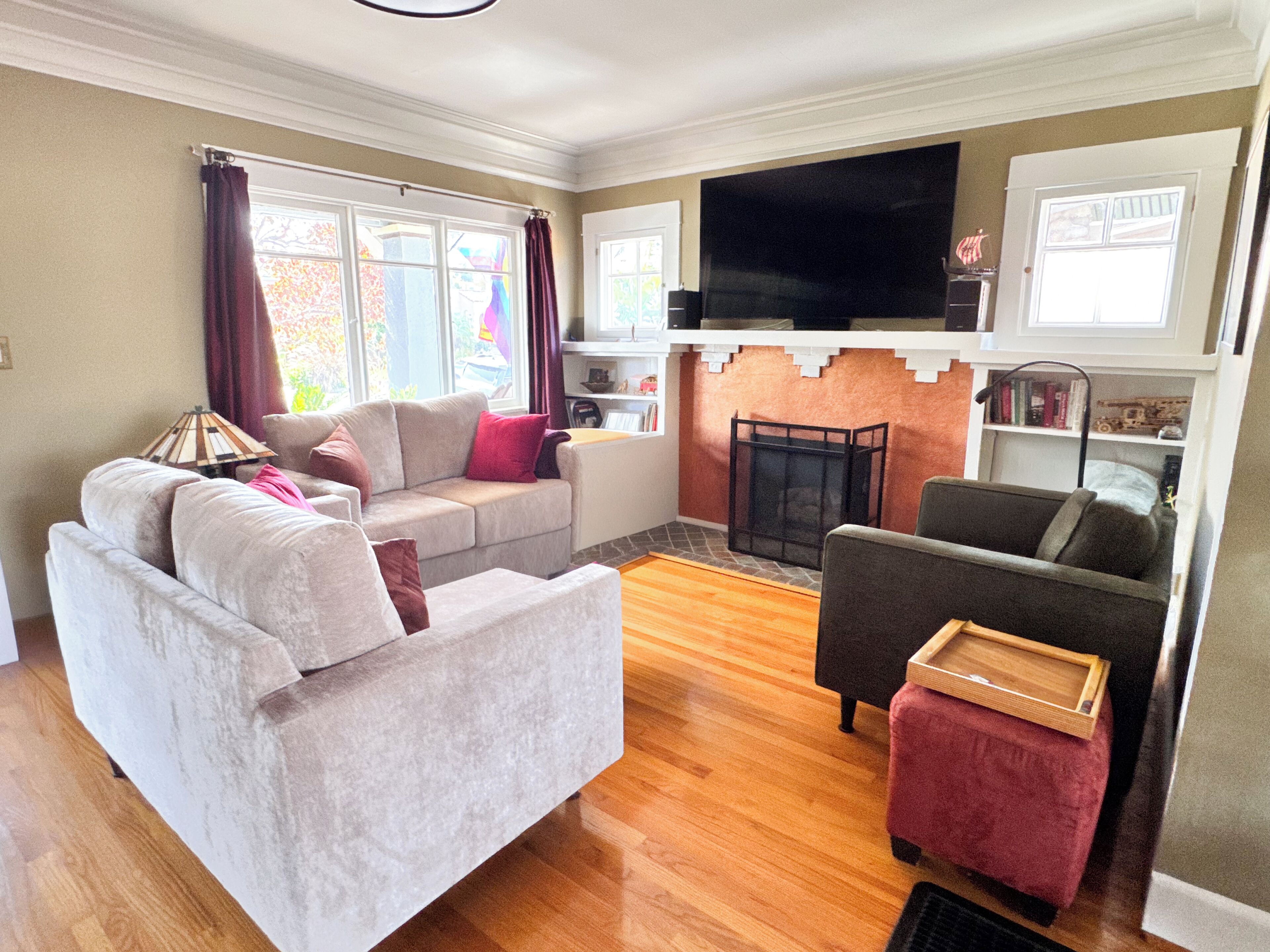 Una sala de estar con sofá, sillón, otoman, chimenea y televisor.