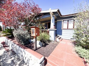 A house with a mailbox, a stone wall, and a red pathway leading to the entrance. - Cozy North Park Home with tranquil patios, AC, located near Balboa Park. (San Diego)