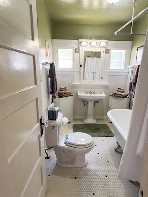 Un bagno compatto con WC, lavandino e vasca da bagno. Sul pavimento, asciugamani e un tappeto verde.