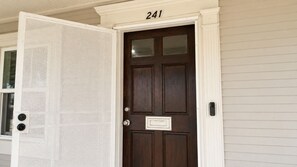 A dark brown front door with a white number plate displaying '241'.