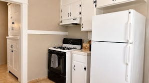 A kitchen with white cabinetry, a black stove, and a white refrigerator. - Cozy 2BR Home with King Bed + In-Unit Laundry (Lemoore)