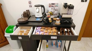 Una kitchenette equipada con cafetera, hervidor de agua, cestita de pan y refrigerador.
