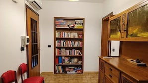 Una habitación con una estantería, un armario de madera y dos sillas rojas.