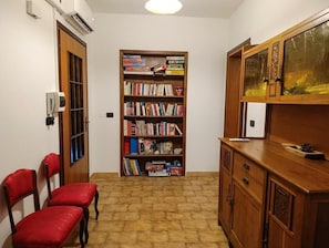 A room with a bookshelf, a wooden cabinet, and two red chairs.