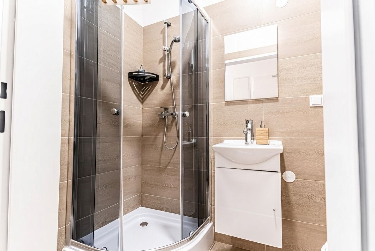 Une salle de bain moderne avec une douche à parois de verre, un lavabo blanc et un miroir au-dessus.