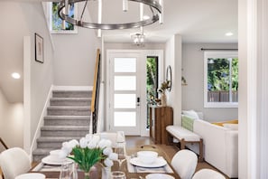 A modern interior with a staircase, dining area, and a living room with a sofa and a window. - Spacious Kirkland Home Near Microsoft & Google (Kirkland)