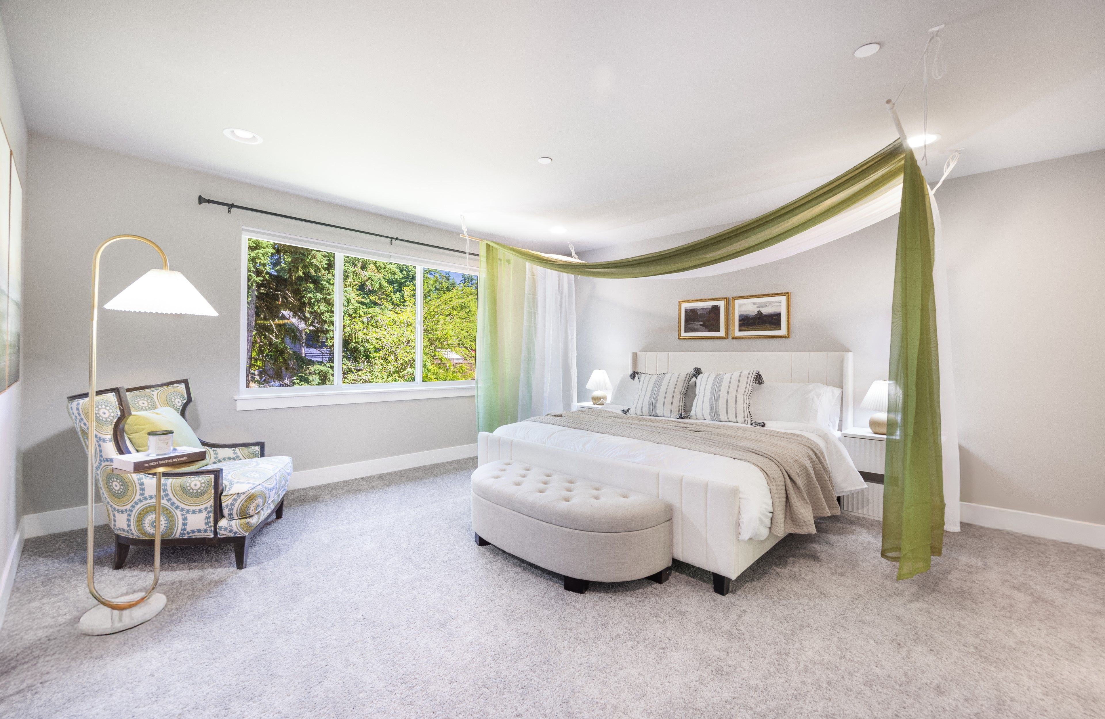 A bedroom with a large window, a bed with a canopy, a chair, and a floor lamp.