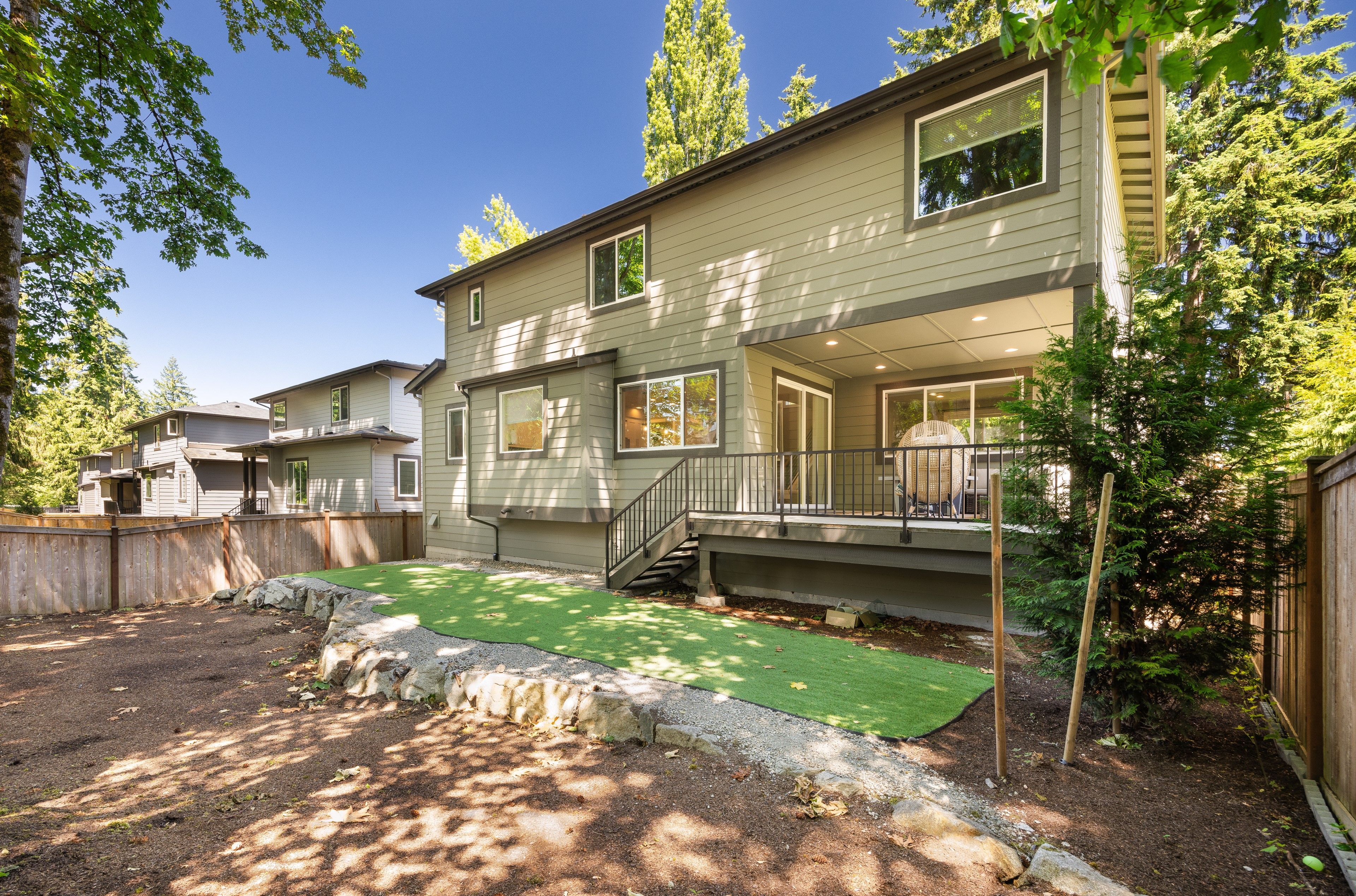 A two-story house with a covered porch and a small backyard with artificial grass.