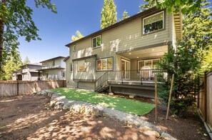 A two-story house with a covered porch and a small backyard with artificial grass. - Spacious Kirkland Home Near Microsoft & Google (Kirkland)