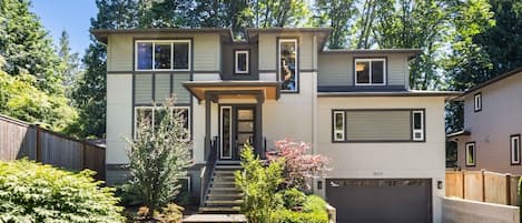 A two-story house with a front entrance, a garage, and a well-maintained garden.