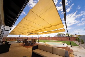 An outdoor patio area with a covered seating area, a hot tub, and a pool. - The Pearl · Backyard, Hot Tub & Park Next Door (Mesa)