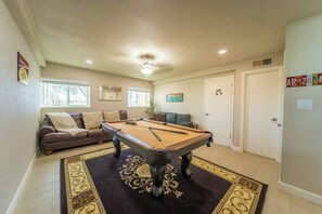 A pool table in a room with a sofa, a potted plant, and a door with a music note symbol. - The Pearl · Backyard, Hot Tub & Park Next Door (Mesa)
