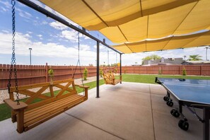 A covered outdoor area with a ping pong table, wooden swings, and a concrete floor. - The Pearl · Backyard, Hot Tub & Park Next Door (Mesa)