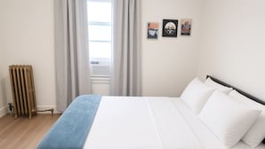 Un dormitori amb un llit, un radiador i tres quadres al mur.