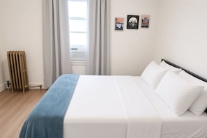 Une chambre à coucher avec un lit, un radiateur et trois tableaux encadrés accrochés au mur.