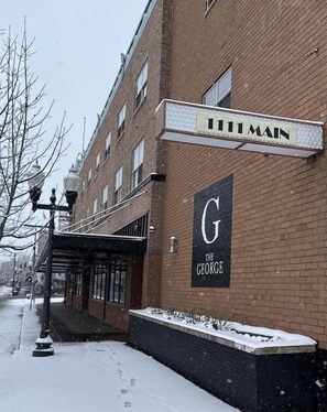Un bâtiment en briques avec une enseigne indiquant « 1111 MAIN » et une grande enseigne « G THE GEORGE » sur le côté.