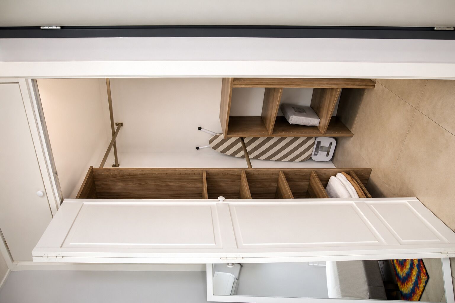 A compact room with a built-in bed, wooden storage compartments, and a small seating area.