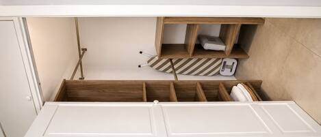 A compact room with a built-in bed, wooden storage compartments, and a small seating area.