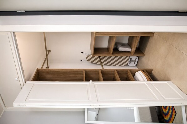 Quarto compacto com cama embutida, compartimentos de armazenamento em madeira e um pequeno espaço para sentar.