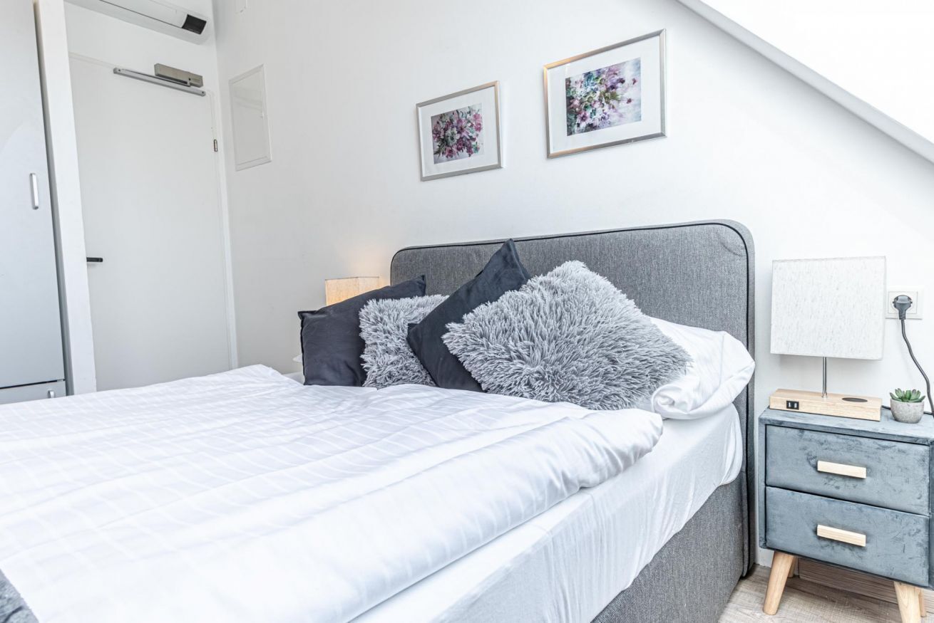 Une chambre à coucher moderne avec un lit, des tables de chevet et des œuvres d’art accrochées au mur.